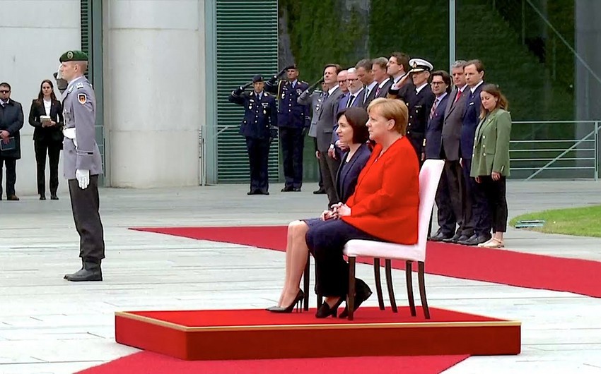 Angela Merkel himni yenə oturaraq dinləyib